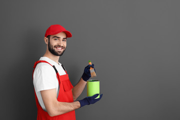 Canvas Print - Male decorator holding brush and paint can on grey background