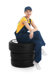 Poster - Female mechanic with car tires on white background