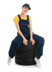 Poster - Female mechanic with car tires on white background