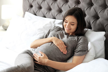 Wall Mural - Young pregnant woman lying on bed at home