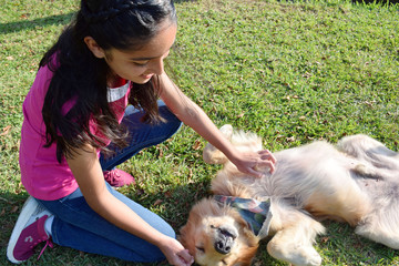 smiling girl playing with dog on the grass