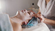 © KONSTANTIN SHISHKIN - Woman getting a cosmetic procedure - mask facial massage at spa salon skincare