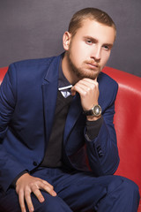 Wall Mural - serious young man in a suit on the sofa