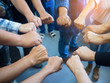 © meeboonstudio - Closeup image of many people putting their fists together as symbol of unity with sunlight effect.