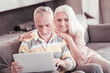 © Viacheslav Yakobchuk - Interesting information. Satisfied pleasant senior woman looking at the screen of the laptop smiling and leaning on her husband.