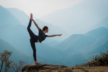 Young Woman Practices Yoga On Mountain Cliff At Sunrise. Mountanious Landscape