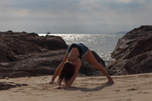Young Woman Practicing Yoga On The Beach