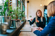 © bnenin - Two friends enjoying a cup of coffee as they sit at the table near the window.