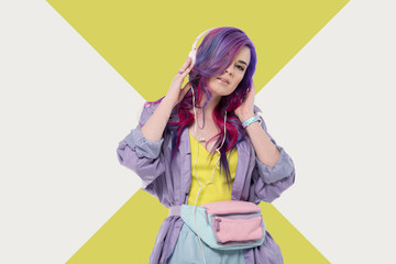 Wall Mural - fashionable young woman with colorful hair in purple trench coat listening music with headphones