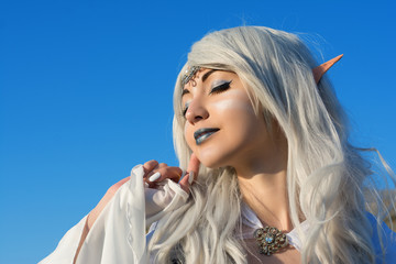 closeup portrait of a beautiful young girl elf. against the blue sky