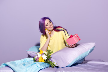 Wall Mural - beautiful young woman with gift box and flowers sitting in bed and talking by phone