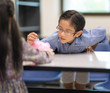 © Nattanon - Selective focus at pig jar. Kids playing collect money with a pink saving Pig Jar in the Library. Setup studio shooting.