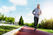© lordn - Man jogging in the morning out on the race track