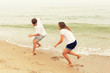 © AnastazjaSoroka - Two teenagers: a girl and a boy with blond hair, dressed in white T-shirts they run, laugh and play in the sea beach.