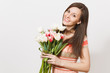 © ViDi Studio - Beautiful young smiling brunette woman in light patterned dress is holding bouquet of white and pink tulips in hands, smiling and rejoices isolated on white background. Concept of holiday, good mood.