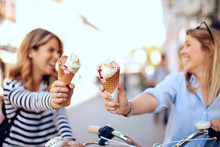 Two Young Women Holding Ice Cream In The City On A Sunny Day