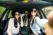 © F8  \ Suport Ukraine - Three young girls having fun in the car and taking selfies with camera