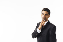 Portrait Of A Confident Young Man In Business Suit Looking Up With Fingers On Chin, Isolated On White Background