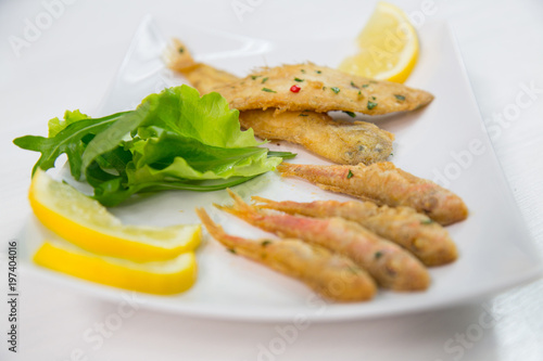Zdjęcie XXL Smażąca ryba na naczyniu z cytryną i sałatką. Typowe sycylijskie jedzenie
