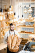 © rh2010 - Handsome bread seller with basket full of baguettes in the beautiful store with bakery products