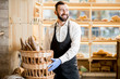 © rh2010 - Bread seller with basket full of baguettes in the store with bakery products