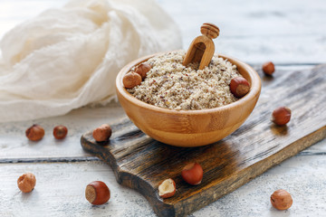 Wall Mural - Hazelnut flour in wooden bowl and whole hazelnut.