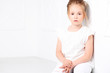 © Raisa Kanareva - Children's fashion. Beautiful pensive serious blonde girl in white clothes. Fashion and people concept.