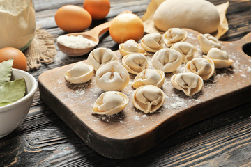 Wall Mural - Wooden board with raw dumplings and products on table