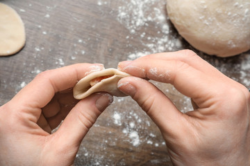 Poster - Woman preparing dumplings at table in kitchen