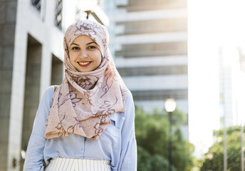 Poster - Islamic woman standing and smiling  in the city