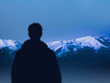 © ruslanshug - silhouette traveler man looks at mountain range. sportsman mountaineer before climbing. concept active lifestyle and achieving goal