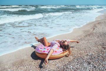 Girl relaxing on donut lilo on the beach