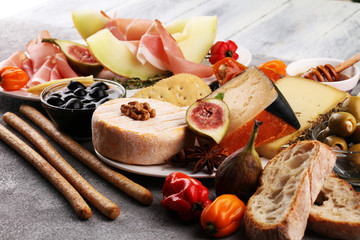 Italian antipasti wine snacks set. Cheese variety, Mediterranean olives, pickles, Prosciutto di Parma with melon, salami.