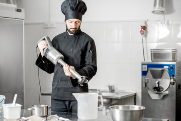 chef cook mixing milk with sugar with professional blender for ice cream production in the small man