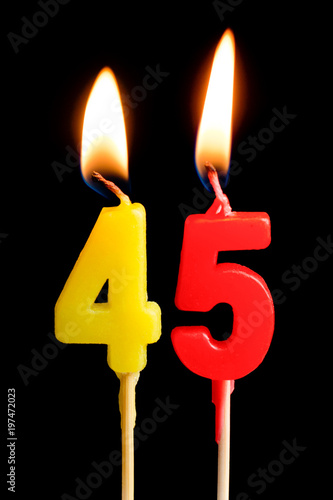 Photographie Burning candles in the form of 45 forty five figures (numbers, dates) for cake isolated on black background