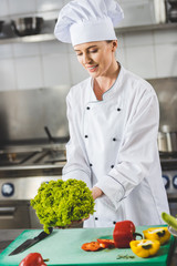 Wall Mural - attractive chef holding lettuce leaves at restaurant kitchen