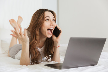 Canvas Print - Portrait of a cheerful young woman talking on mobile phone