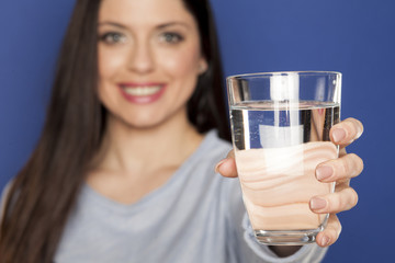 A young lady holding a glass with wather on a blue background