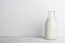 Full Glass Bottle Of Milk On White Wooden Table Background With Copy Space