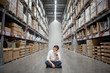 © zephyr_p - Young Asian man sitting in warehouse choosing what to buy, shopping warehousing concept