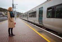Young Woman Standing On Platform In Front Of Train