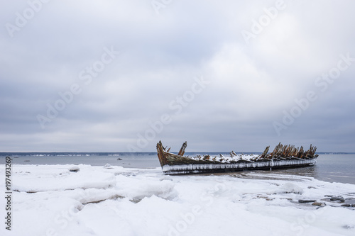 Old broken boat wreck and rocky beach in wintertime Poster
