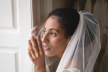 Bride In Wedding Dress Looking Through Window