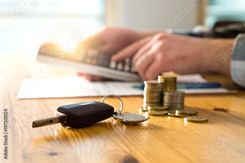 Fotografía Car keys and money on table with man using calculator