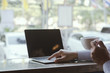 © thithawat - attractive hand of business man using laptop working typing on key board with coffee cup in coffee shop.