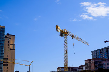 Wall Mural - Tower building crane against the blue sky and sun. Construction of new buildings with a crane. Tower crane