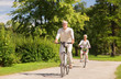 © Syda Productions - active old age, people and lifestyle concept - happy senior couple riding bicycles at summer park