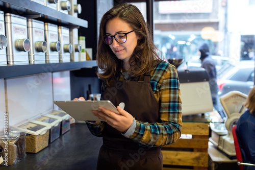 Cuadros en Lienzo Beautiful young saleswoman doing inventory in a retail store selling coffee