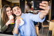 © F8  \ Suport Ukraine - Happy beauty couple eating burger and doner taking selfie together in fast food