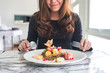 © Farknot Architect - A beautiful asian woman enjoy eating fruits salad on the table in restaurant